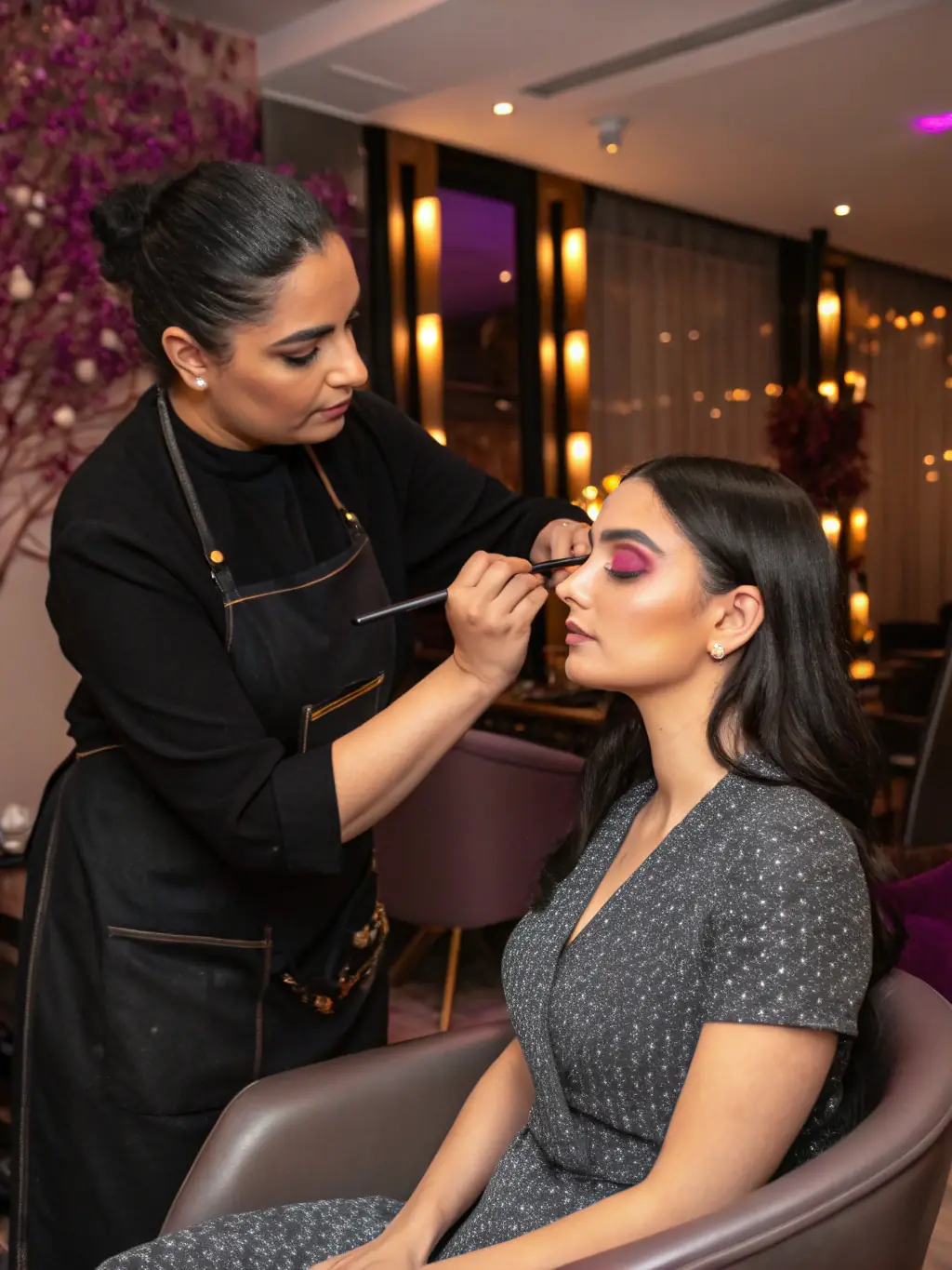 A client relaxing in a comfortable makeup chair, being pampered by a makeup artist in a beautifully decorated studio, conveying a sense of luxury and relaxation.